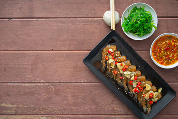 Prawns pickled in soy sauce or shoyu sauce and sprinkled with chili and sliced garlic with spicy sauce Seaweed and Japanese rice are side dishes on a brown wooden table.