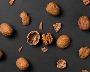 Whole walnut and pieces of shell on black background.