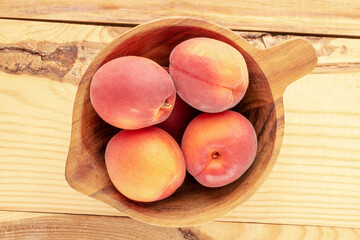 Several organic apricot reds in a wooden bowl on a wooden table, close-up, top view.