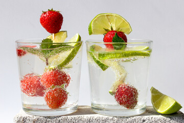 Carbonated drink with lime slices and strawberries in glasses decorated with mint leaves