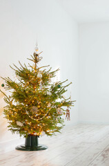 christmas tree with decor and lights in white room