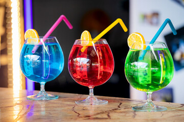 Three colorful bright cocktails with a straw and a slice of lemon. Chemical composition and unhealthy alcohol