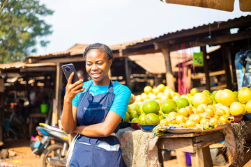 excited African market woman using mobile phone