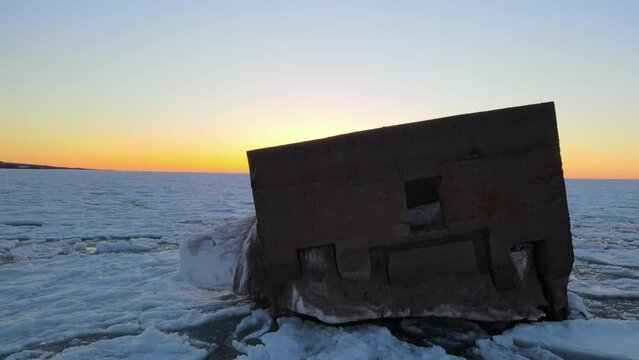 View of an abandoned wooden boat pulled ashore on the cracked icy ground in Duluth, Minnesota, US