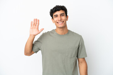 Young Argentinian man isolated on white background saluting with hand with happy expression