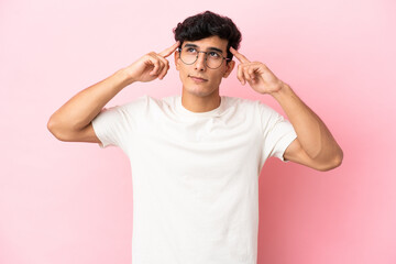 Young Argentinian man isolated on pink background having doubts and thinking