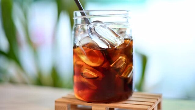 Big glass with cold brewed coffee and ice, black straw 