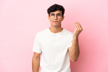 Young Argentinian man isolated on pink background making Italian gesture