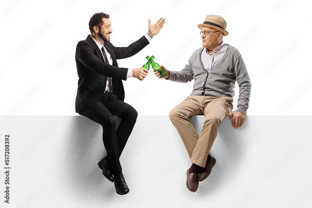 Poster Elderly man and a happy businessman sitting on a blank panel and toasting with bottles of beer