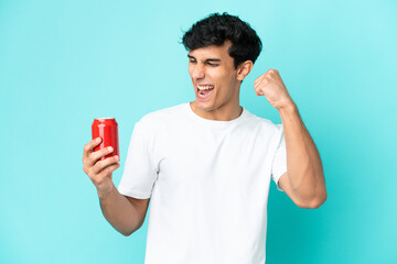 Young Argentinian man holding a refreshment isolated on blue background celebrating a victory