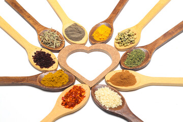 Different kind of spices on a white background.  Oriental spices in spoons, red peppers, curry powder, cinnamon powder, mint powder, sumac, sesame, black cumin, . Flat lay, top view. Heart Shape. 