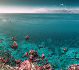 Aerial scenic panoramic seascape view from a high cliff. Vacation background and coastline concept. Azure sea bottom and sailing motor boat