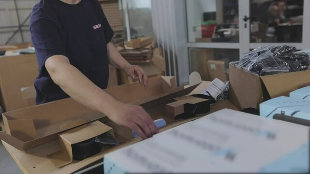 Packaging of finished goods in a box. Workers pack finished products into a box