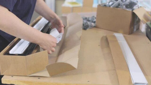 Packing plastic parts in a box. The worker puts the goods in a box for sending to the client