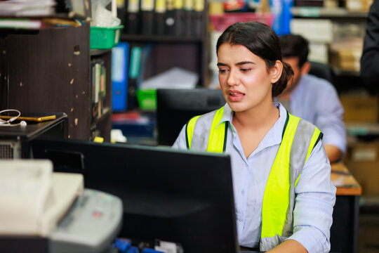 Asian Indian beautiful woman warehouse worker checking order  in desktop computer at office warehouse factory. Check emails.