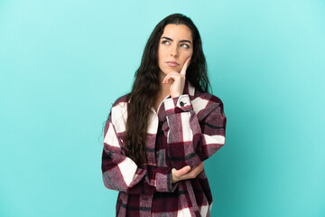 Young caucasian woman isolated on blue background and looking up