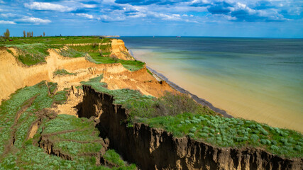 Ruined clay slope by the sea. Cracked clay cliff on the coast. A crumbling and cracked clay wall on...