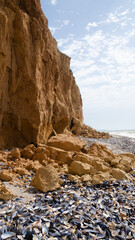 Ruined clay slope by the sea. Cracked clay cliff on the coast. A crumbling and cracked clay wall on the beach.