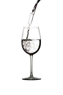 A splash of crystal clear water in a glass for wine. Water splashes. Drinking water. Alcohol. Isolated on white background