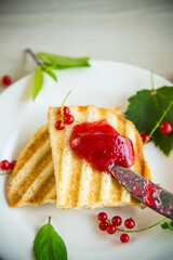fried bread croutons for breakfast with redcurrant jam in a plate with berries