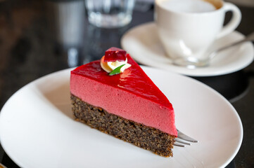Piece of famous Poppy seed cake with raspberry mousse of Austrian origin served with whipped cream and cup of coffee