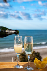 Outdoor breakfast with Spanish cava sparkling wine and pineapple with view on blue sea and sandy...