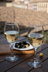 Two glasses of Spanish dry rueda white wine served with olives on roof terrace with view on old part of Andalusian town Granada, Spain