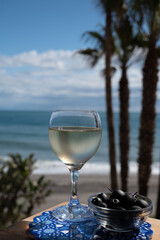 Spanish dry rueda white wine and black olives tapas served on beach terrace with view on Mediterranean sea