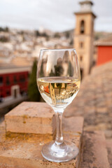 Glass of Spanish dry rueda white wine served on roof terrace with view on old part of Andalusian town Granada, Spain