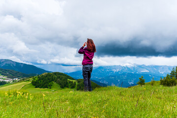 Naklejka premium A wide angle shot of a young female hiker on a break during a hike on a cloudy summer day in the French Alps (Valberg, Alpes-Maritimes, France)