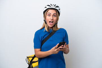 Young caucasian woman with thermal backpack isolated on white background surprised and sending a message