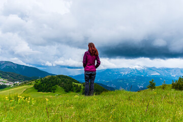 Naklejka premium A wide angle shot of a young female hiker on a break during a hike on a cloudy summer day in the French Alps (Valberg, Alpes-Maritimes, France)