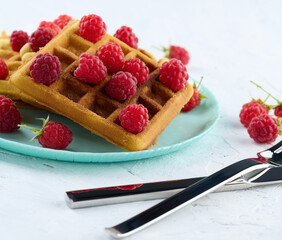 Stack of baked Belgian waffles with ripe red raspberry
