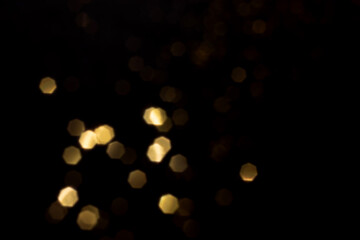 Golden blurred bokeh lights on black background. Glitter sparkle stars for celebrate. Overlay for...