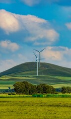 Vertical shot of windmill turbines in a field in Mongolia © Chuck_yept/Wirestock Creators