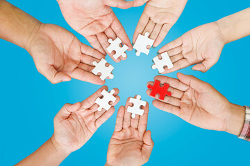 Close up Businesspeople hand holding jigsaw puzzle in a circle on the table on blue background, success and strategy concept.