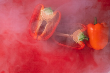 SWEET, fresh RED PEPPER ON A RED BACKGROUND, cut in half, thick smoke around. photo for the menu, proper nutrition. fresh vegetables