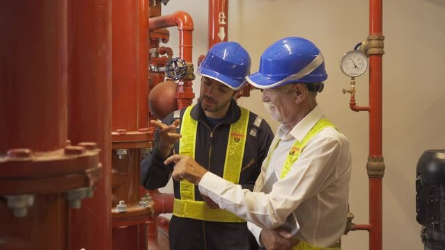 Engineer men or worker team, people working in industry factory. Chiller tower on rooftop building. Fire protection system work machine. Condenser Water Supply pipe lines.