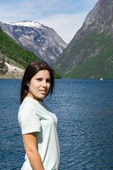 Young tourist woman in the foreground and behind her the fjord with the high mountains in Gudvangen - Norway
