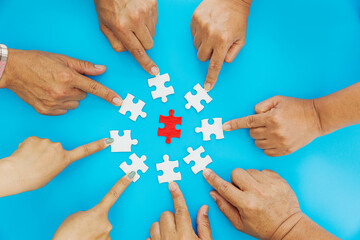 Close up Businesspeople hand holding jigsaw puzzle in a circle on the table on blue background, success and strategy concept.