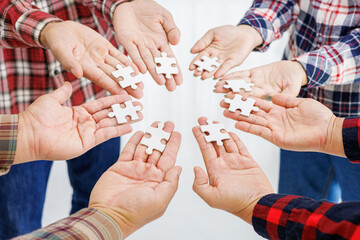 Close up Businesspeople hand holding jigsaw puzzle in a circle on the table, success and strategy concept.