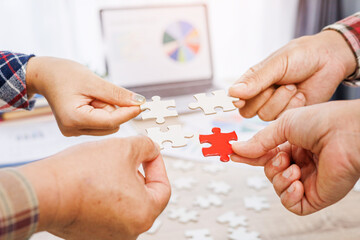 Close up Businesspeople hand holding jigsaw puzzle in a circle on the table, success and strategy concept.