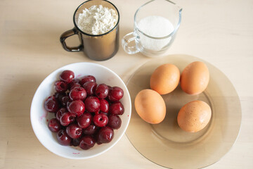ingredients for making cherry pie, sugar, eggs, flour stand on a light table surface. Home baking