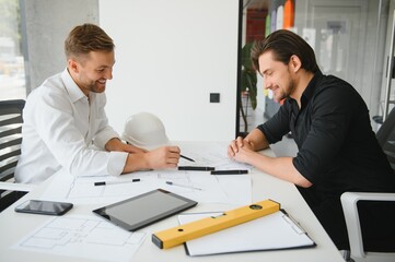 two people sit in front of construction plan and talk about the architecture