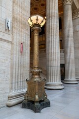 Vertical shot of a golden medieval lamp next to Corinthian columns