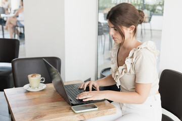young woman having a coffee while working with the laptop