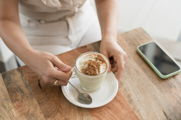 young woman's hands holding tea and phone