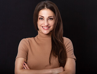 Fototapeta premium Beautiful young business toothy smiling woman thinking and looking happy on dark black background with empty copy space. Portrait