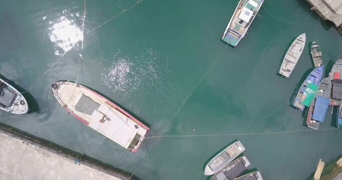Aerial top view of several boats docked near the concrete shore in Batanes, Philippines