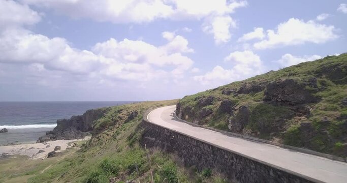 Drone footage of a road passing through the mountainous shore of Batanes, Philippines on a sunny day